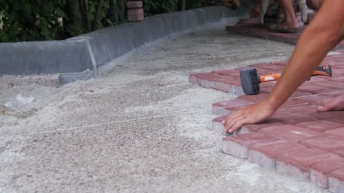 Construction Worker Laying Red Bricks With a Rubber Hammer