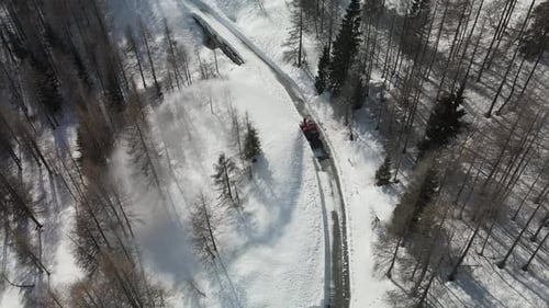 Aerial top down of snowplow clearing road. Beautiful white snow forest