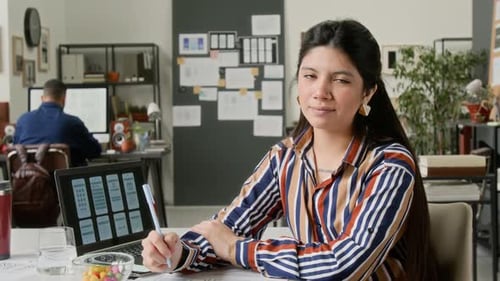 Portrait of Hispanic Female User Interface Designer at Work Desk in Office