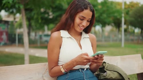 Smiling Woman Using Smartphone on Park Bench