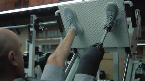 Sportsman with Prosthetic Leg Trains on Leg Press Machine in Gym