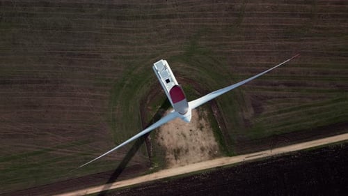 Luftaufnahme einer Windturbine auf Ackerland von oben, die die riesigen Rotorblätter und die Umgebung zeigt
