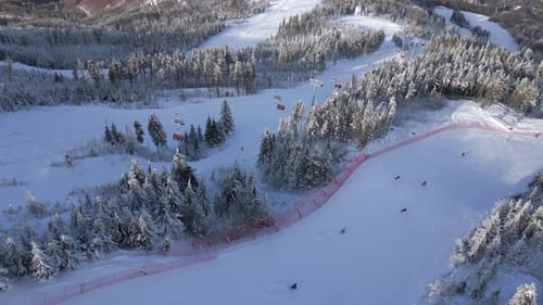 Aerial of Snowy Ski Slope with People Skiing and Chairlifts in Mountain Resort