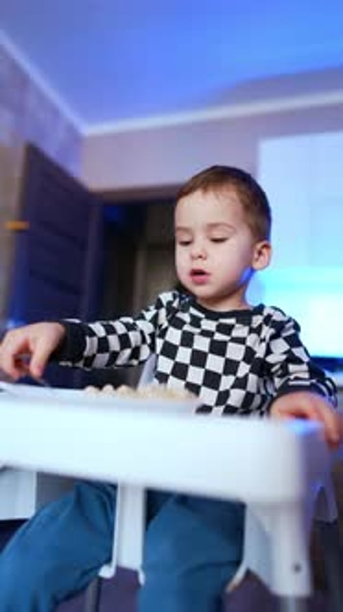 Child in High Chair Eats Food