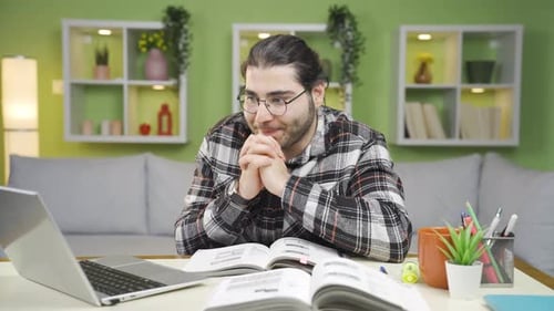 Young Adult Studying at Home with Laptop and Book