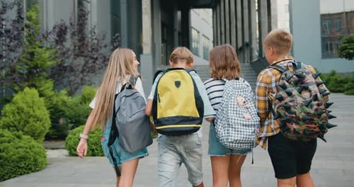 Group of cheerful energetic students child girl boy go to modern campus school with school backpacks