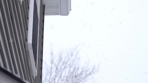 Small snowflakes falling down on a cold winter day, grey sky, slow ...