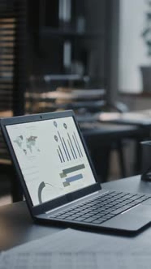 Laptop with Financial Charts on Screen at Office Table