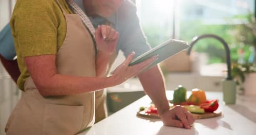 Couple Cooking Together Using a Tablet in Sunny Kitchen