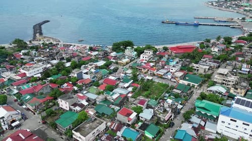 Establishing Aerial View of lively, island town facing idyllic ocean bay with harbours and a lone ro