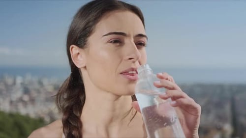 Smiling Woman Drinks Water After Outdoor Workout