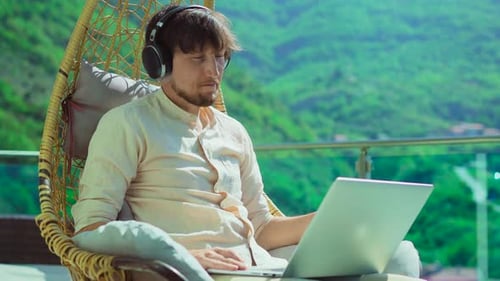 Young Man on Balcony Surrounded By Stunning Mountain Scenery