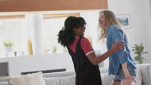 Happy diverse teenage female friends dancing at home, slow motion