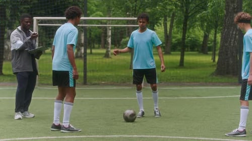 Coach and Youth Players Discussing Game Tactics After Dribble Practice