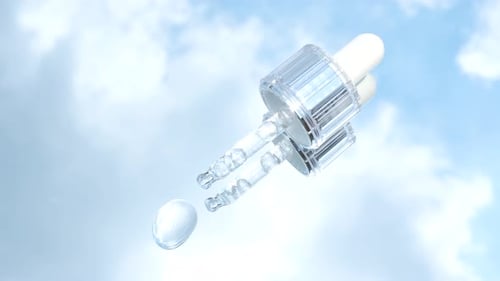 Dropper with serum on the mirror reflected in blue sky.