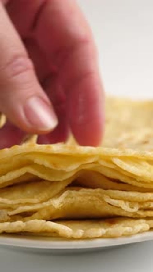 Hand Taking Pancake from Stack on Plate