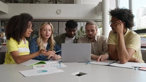 Five Multiethnic University Students Reviewing Data Diagrams Studying Project Study Together with