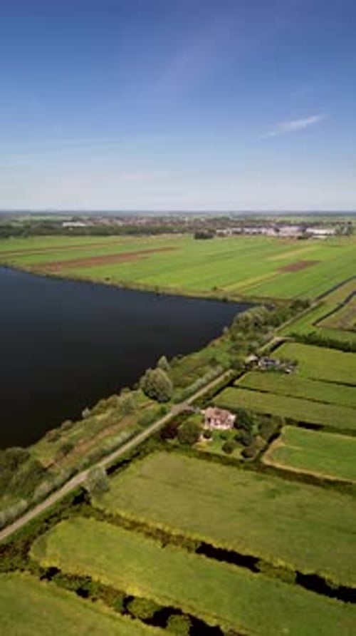 Aerial view of a rural landscape with central road water body irrigated fields and scattered houses