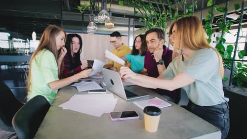 In a Vibrant Office Filled with Lush Green Plants a Dynamic and Enthusiastic Team Gathers to Discuss