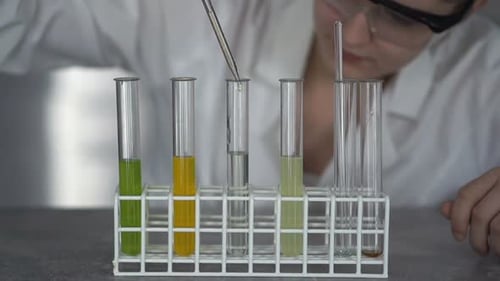 Woman Scientist Pipetting Liquid Into Test Tubes