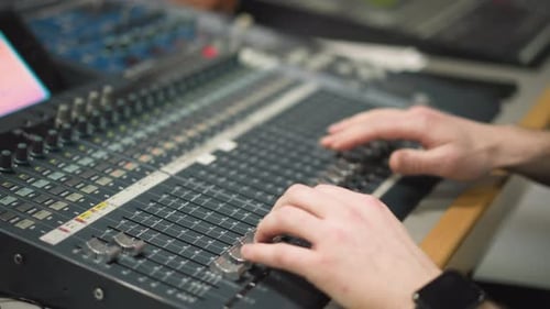 Hands Adjusting Sound Mixer in Recording Studio