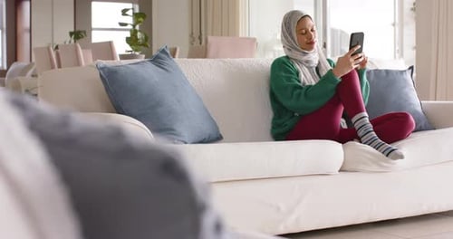 Woman Relaxing on Couch with Mobile Phone Indoors