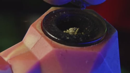 close up shot of breaking up marijuana into a rubber pipe to be smoked