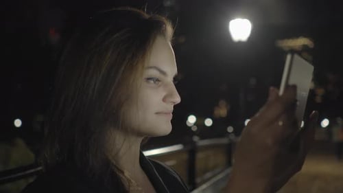 Young Woman Using Tablet Computer In The Park At Night