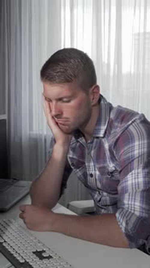 Tired Man at a Desk Using a Computer
