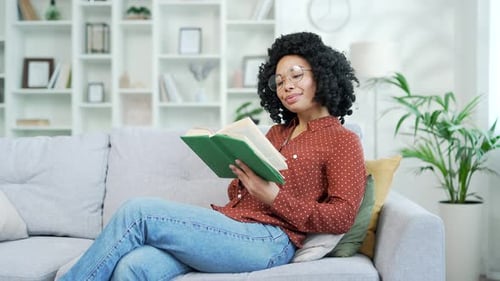 Woman Reading Book on Sofa at Home