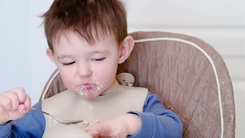 Happy Toddler Eating Cereal in Highchair