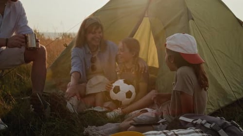 Family Relaxing and Talking by Tent during Camping Trip in Nature