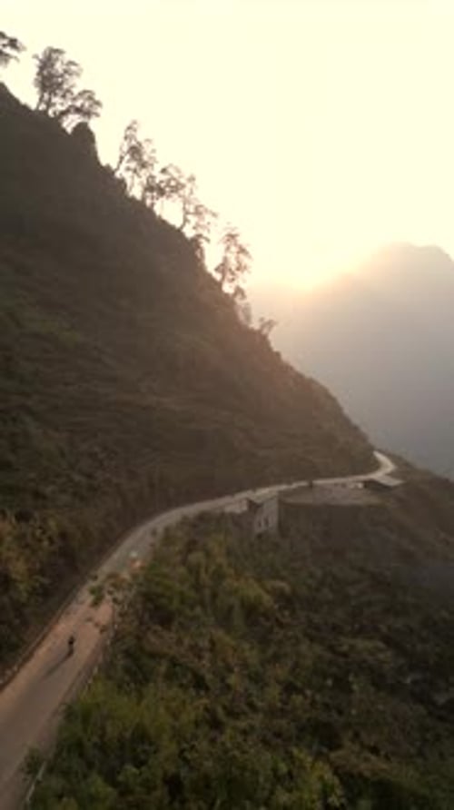 Aerial View Of Motorcycle Riding Along Mountain Road At Sunset Vietnam