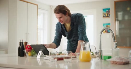 Young Adult Cooking at Home with Tablet Recipe