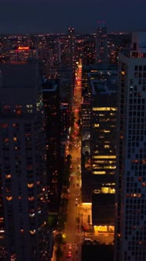 Bright street with many cars going between modern skyscrapers.