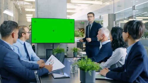 Businessman Gives Report/ Presentation to His Business Colleagues, Pointing at Green Chroma Key Scr
