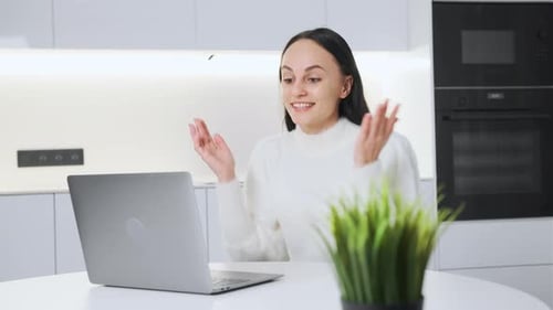 Woman Using Laptop for Video Call in Kitchen