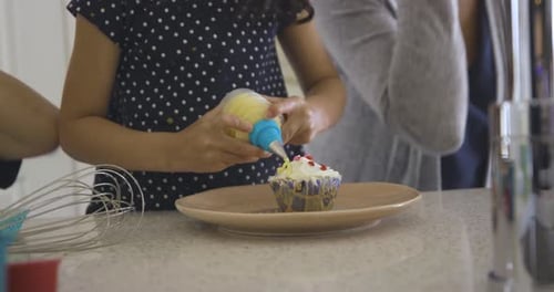 Mädchen dekoriert Cupcakes beim Backen in der Küche, 35—39 Jahre