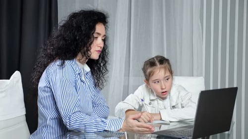 Woman Helping Girl with Homework at Table