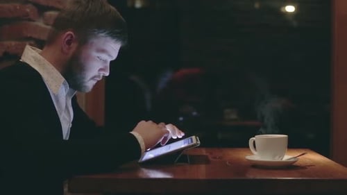 Businessman with Tablet Computer in the Evening Cafe