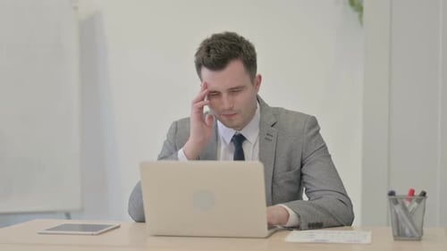 Stressed Young Adult at Laptop in Workplace