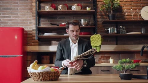 A Businessman is Reading a Newspaper in a Modern Kitchen Setting While Enjoying Breakfast