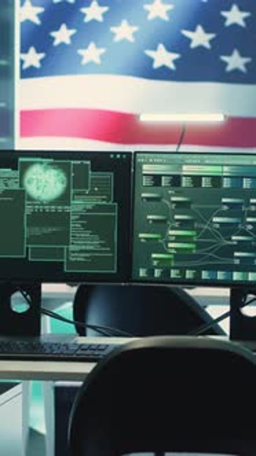 Office with computer screens displaying code and US flag