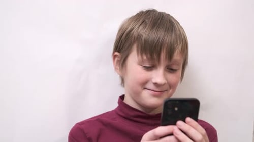 Child Looks at Smartphone and Smiles Indoors