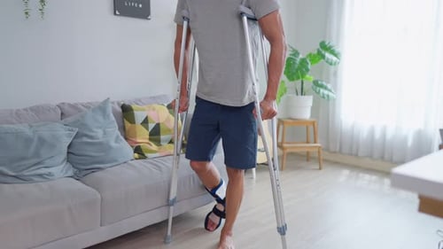 Man with foot injury walks with crutches indoors