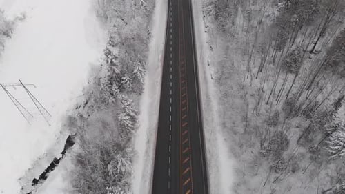 Survoler une route asphaltée dans la forêt d'hiver - prise de vue aérienne par Drone