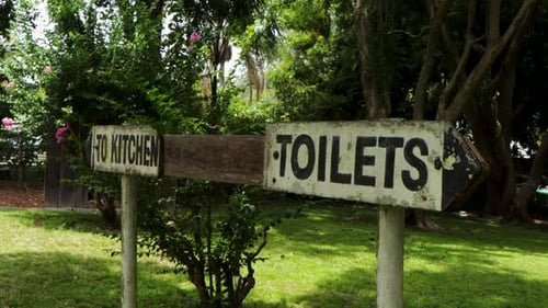 Handheld view of Old To Kitchen and Toilets sign with arrows pointing opposite.