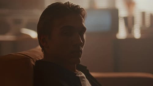Man Sitting in Chair in Dimly Lit Room