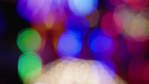 Defocused bright lights flash at a fun carnival at night. Amusement Park Bokeh Lights at Night.