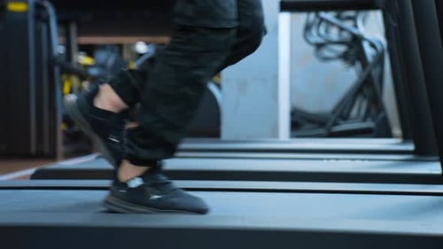 Man training in sport club. Close up athletic feet running on treadmill in fitness gym